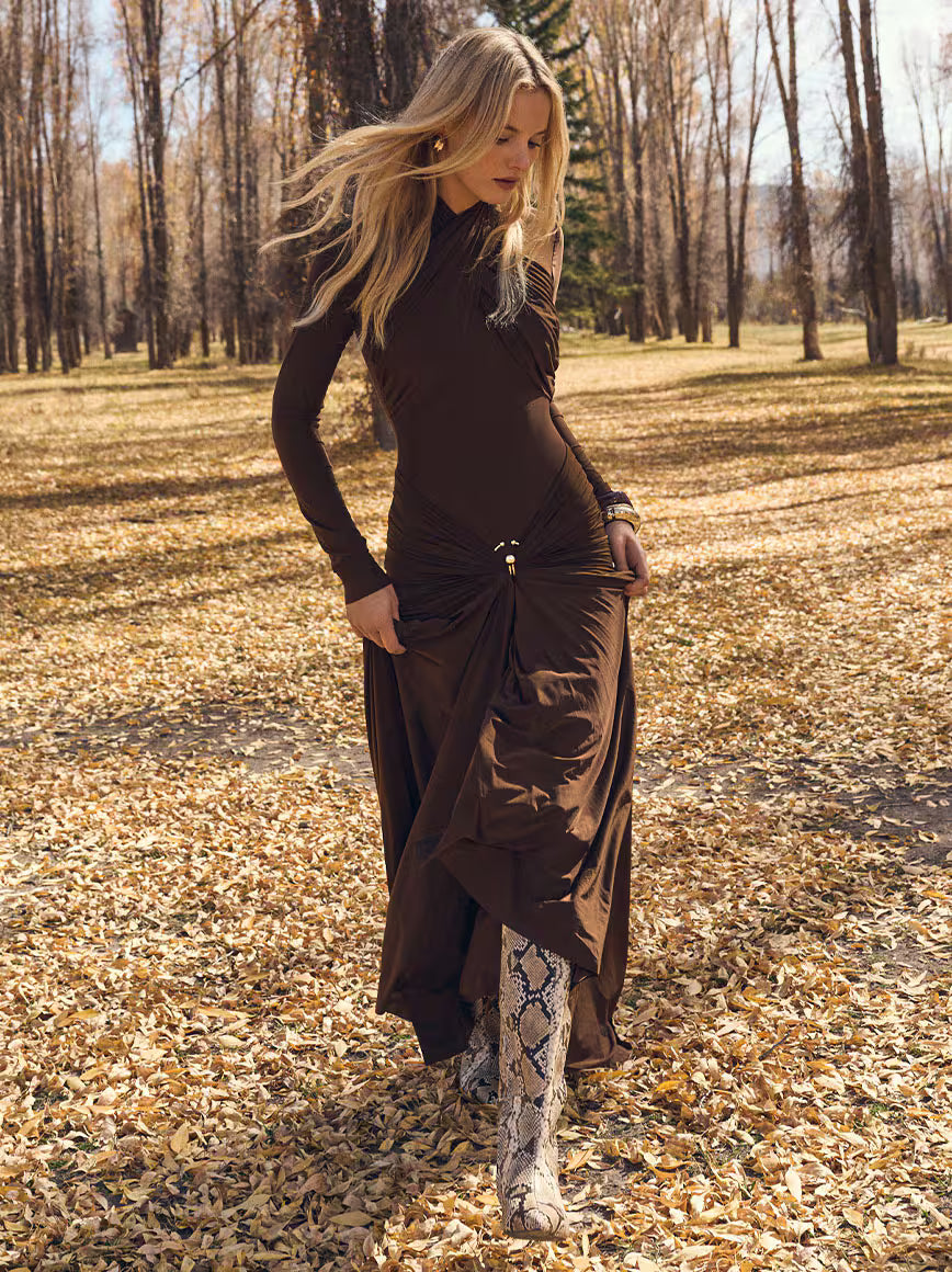 Woman in zebra-patterned dress standing in a garden setting.