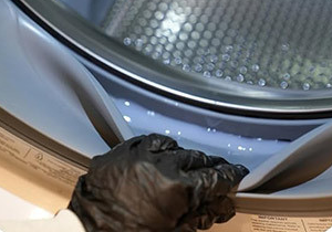 Applying Klenzo gel directly onto a washing machine gasket seal, close view of the wet seal