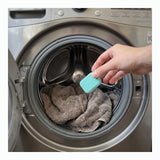 Hand placing a mint washer cleaner tablet into a front load washer