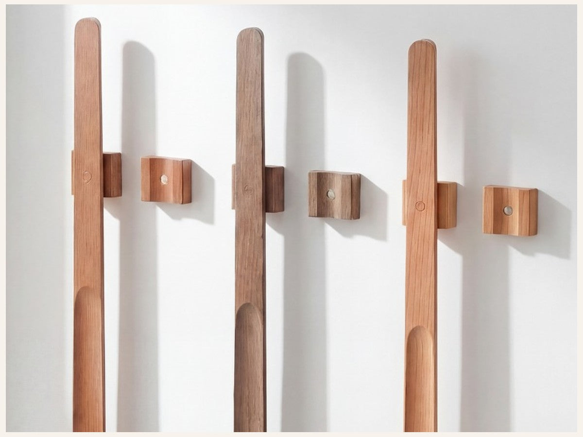 Three Norlund magnetic shoehorns in different wood finishes on a wall