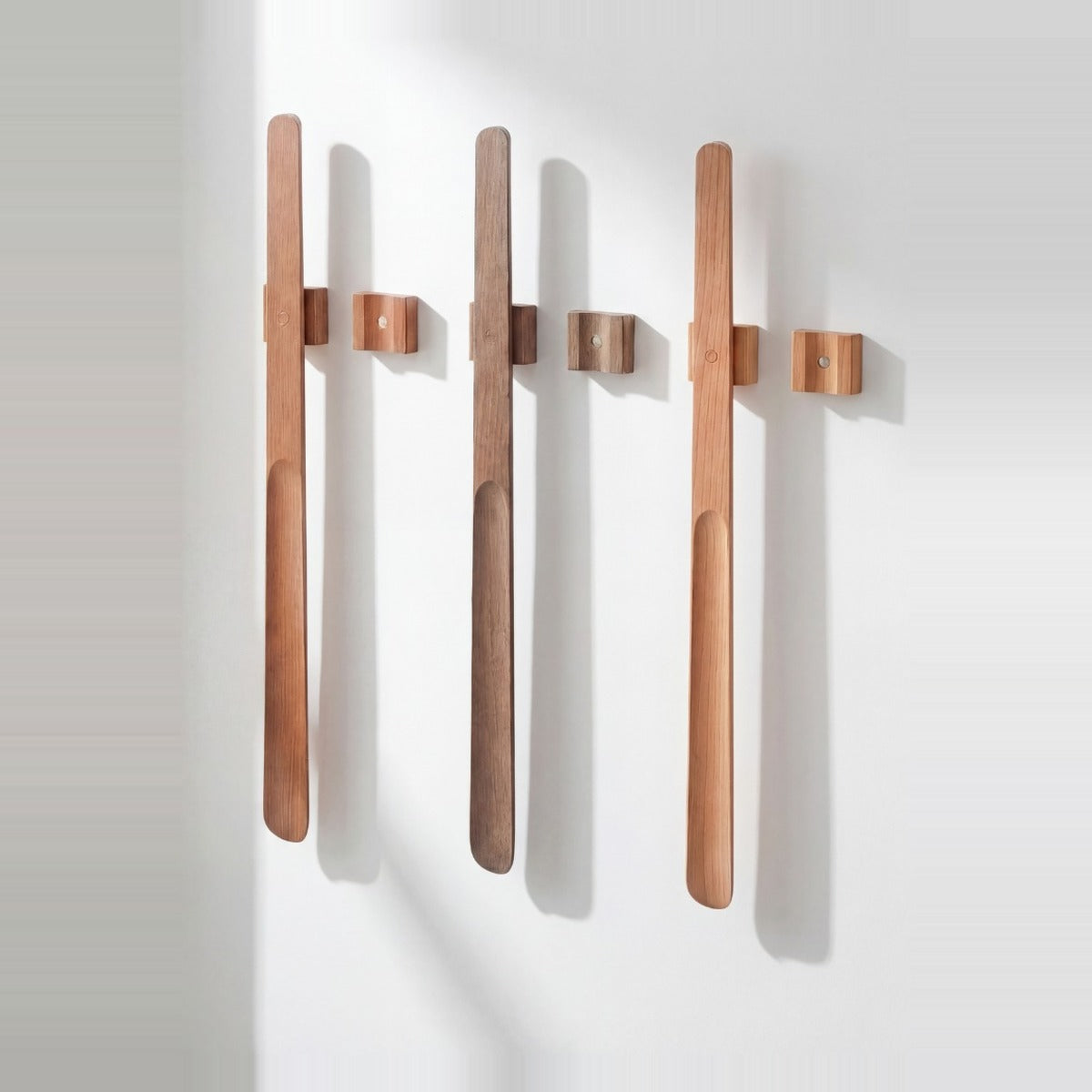 Three Norlund magnetic shoehorns in oak, walnut and light-oak finishes mounted side by side